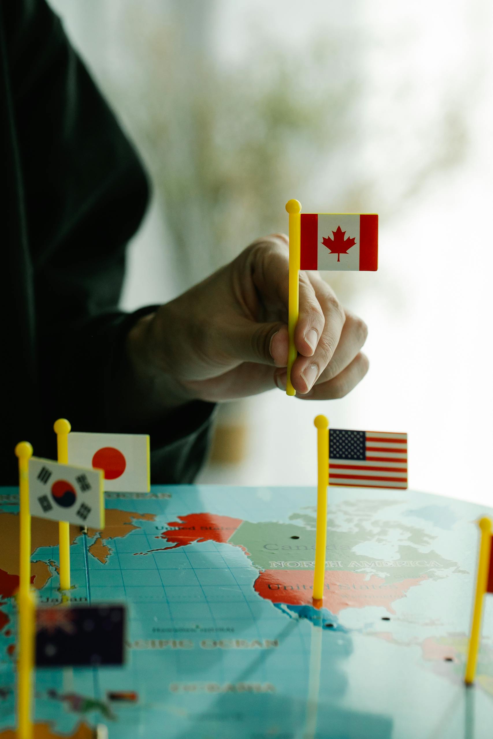 Close-up of a hand arranging mini country flags on a world map.